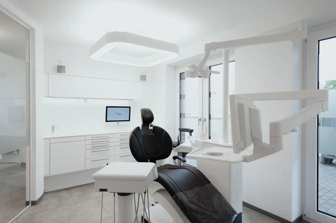 Behandlungsraum mit Behandlungsstuhl, Arbeitsfläche und wandmontiertem Monitor